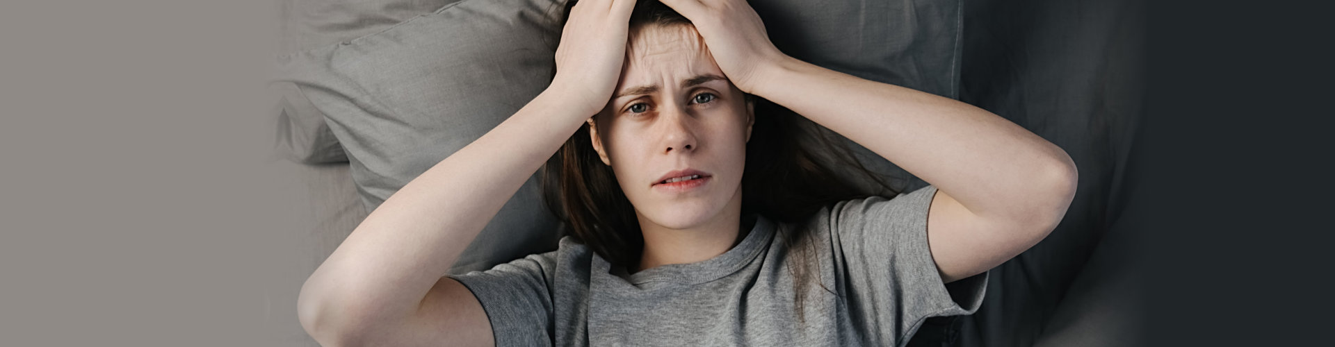 Unhappy young woman lying in bed