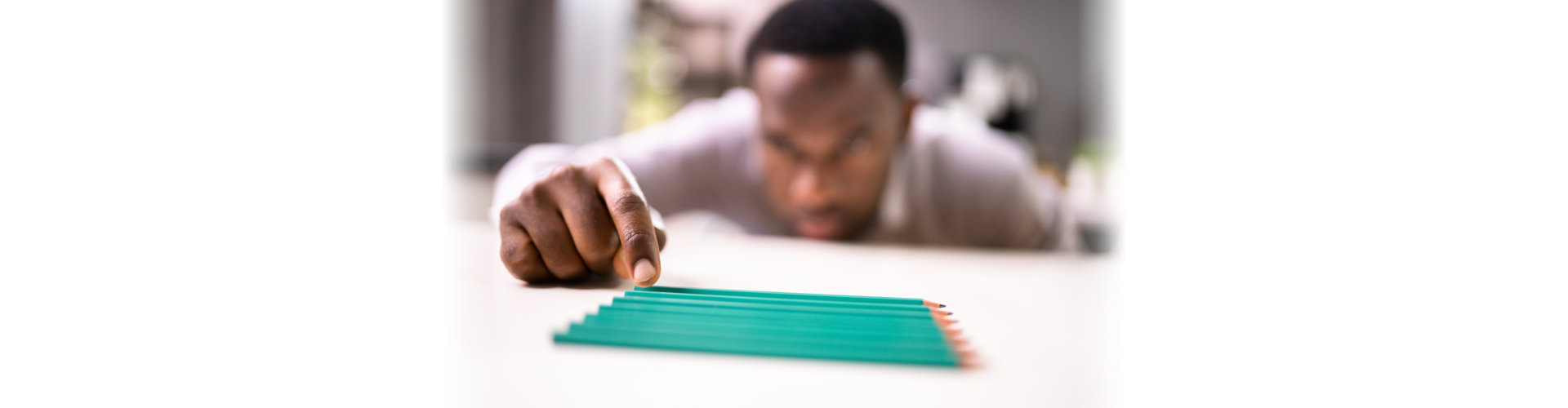 A man aligning up pencils on a table