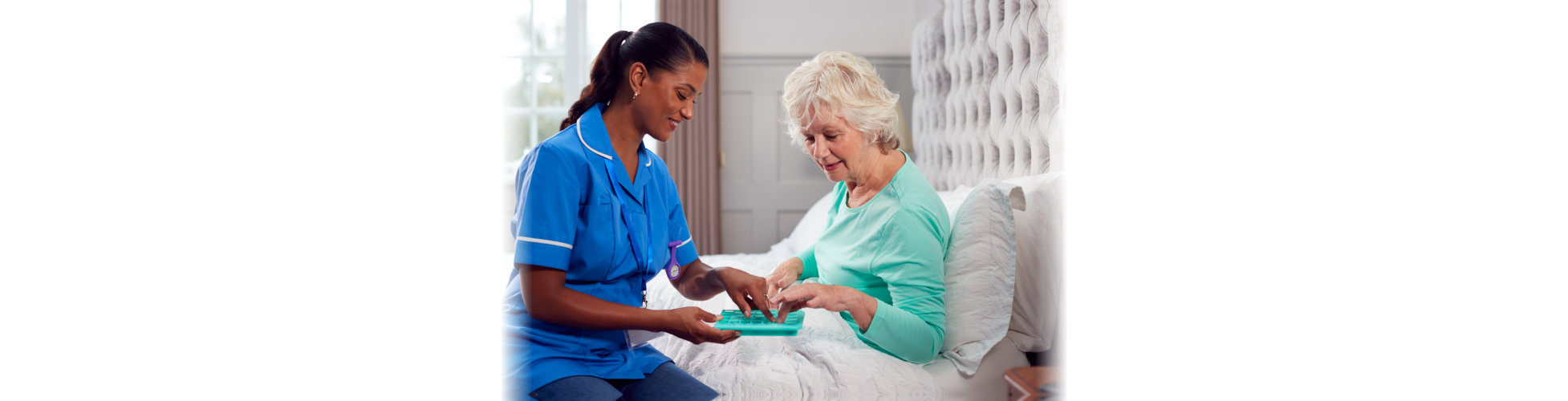 The caregiver helping the elderly woman with her medicine