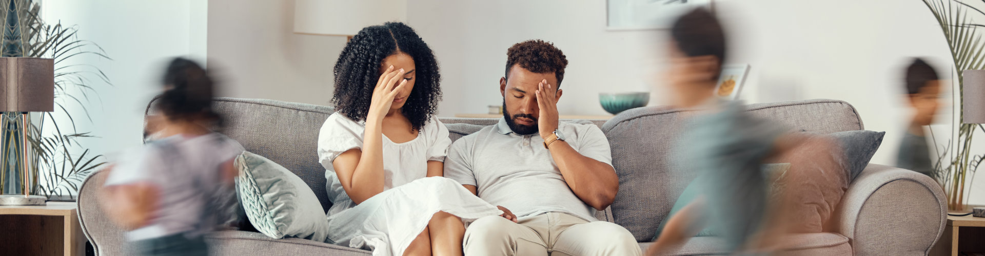 Couple sitting in the sofa while their children are playing